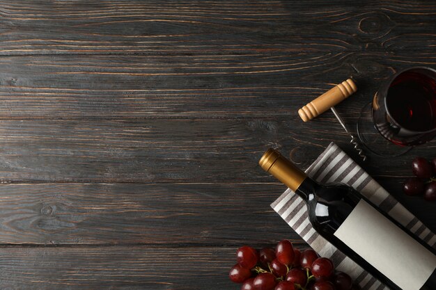 Uva, bottiglia e bicchiere con vino su legno