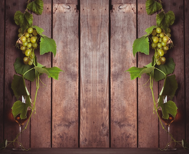 Uva con foglie e bicchiere di vino sullo sfondo di legno