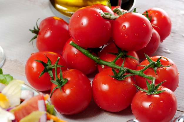 Uva dei pomodori ciliegia sulla tavola di legno bianca