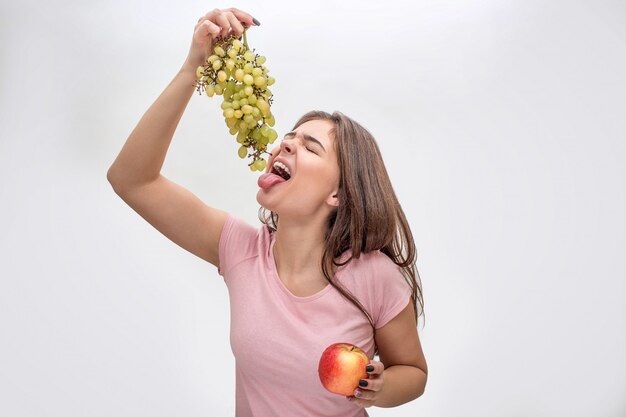 Uva della tenuta della giovane donna sopra la bocca aperta