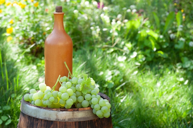 Uva e bottiglia di vino sulla botte di vino