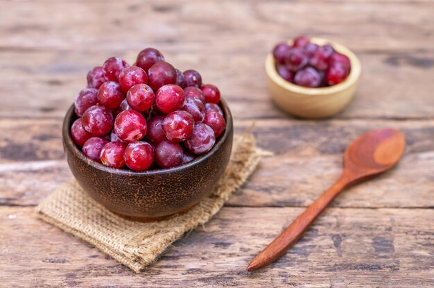 Uva rossa frutta in ciotola di legno su sfondo sfocato