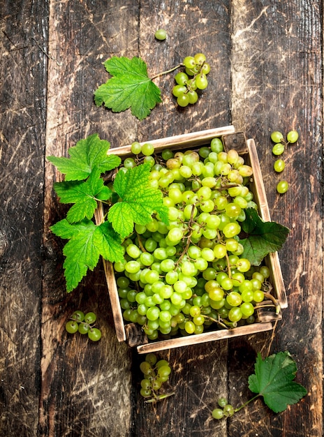 Uva verde in una scatola sulla tavola di legno.