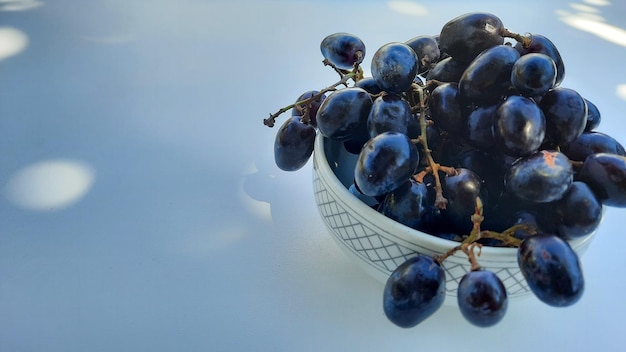 Uva viola in ciotola con gambo isolato su sfondo bianco e ombra 02