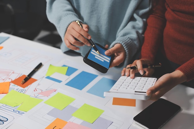 UX UI designer testing prototype on a phone discussing and brainstorming on wireframes for a website and mobile app prototype in the concept of website and mobile application design concept