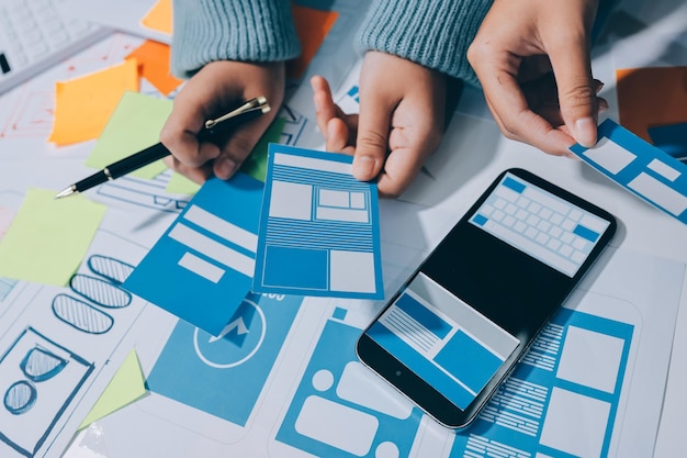 UX UI designer testing prototype on a phone discussing and brainstorming on wireframes for a website and mobile app prototype in the concept of website and mobile application design concept