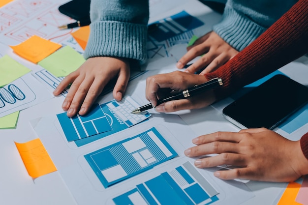 UX UI designer testing prototype on a phone discussing and brainstorming on wireframes for a website and mobile app prototype in the concept of website and mobile application design concept