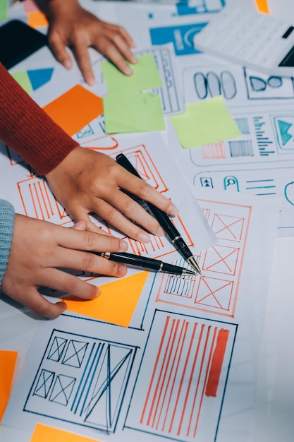 UX UI designer testing prototype on a phone discussing and brainstorming on wireframes for a website and mobile app prototype in the concept of website and mobile application design concept
