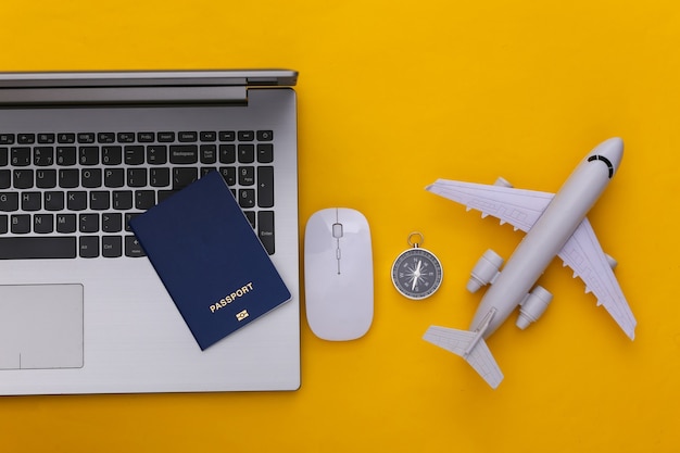 Vacanza di vacanza piatta e concetto di planata di viaggio. Laptop e accessori da viaggio su sfondo giallo. Vista dall'alto