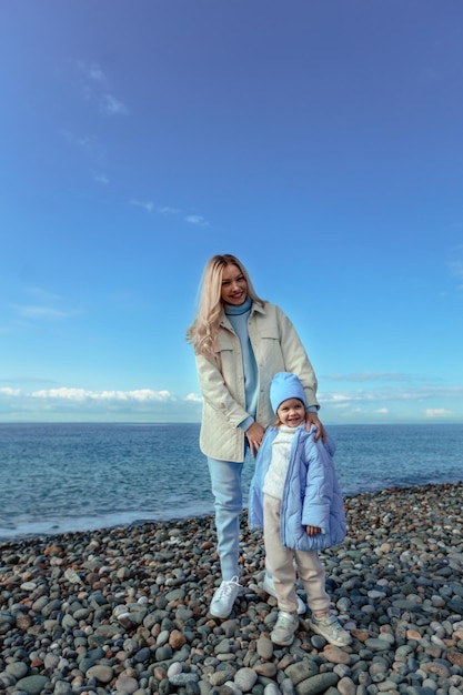 Vacanza in famiglia al mare in autunno o in primavera Famiglia felice madre e figlia in una passeggiata lungo la riva del mare