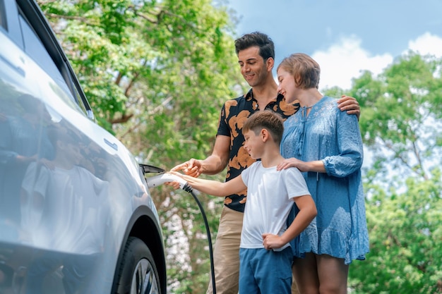 Vacanza in famiglia con un veicolo elettrico bella famiglia ricarica un'auto elettrica con energia verde e pulita Viaggi in auto naturali ed ecologici per un ambiente sostenibile Perpetuo