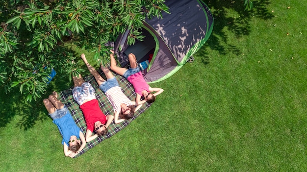 Vacanza in famiglia nella vista aerea dall'alto del campeggio dall'alto, genitori e figli si rilassano e si divertono nel parco, tenda e attrezzatura da campeggio sotto l'albero, concetto di famiglia in campo all'aperto