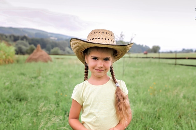 Vacanza locale, stai al sicuro, resta a casa. Bambina in cappello da cowboy che gioca in western nella fattoria tra le montagne, felice estate in campagna, infanzia e sogni