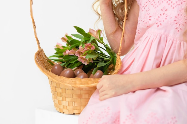 Vacanza Pasqua bambini mano ragazza con cesto di uova di cioccolato fiori primaverili