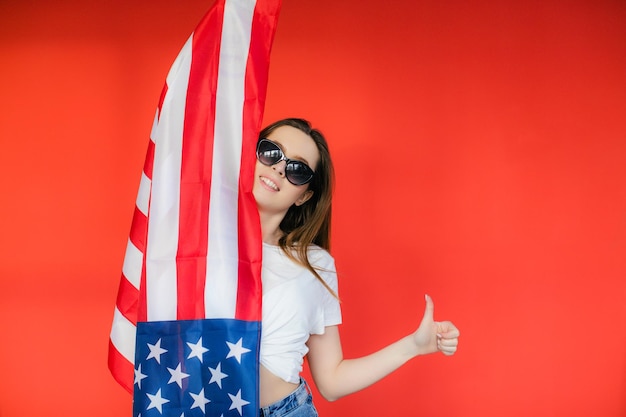 Vacanza patriottica Felice giovane donna con bandiera americana su sfondo rosso USA festeggia il 4 luglio