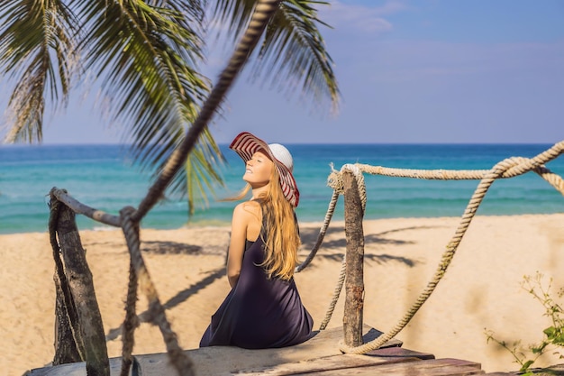 Vacanza sull'isola tropicale Donna con cappello che gode della vista sul mare dal ponte di legno