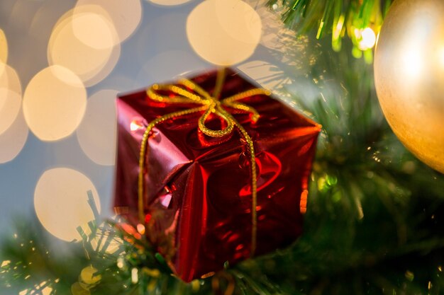 vacanze, capodanno, arredamento e concetto di celebrazione - primo piano della decorazione rossa della confezione regalo sull'albero di natale