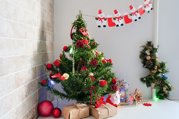 Vacanze, celebrazione e concetto di casa - tavolo da cucina con albero di Natale e regali di carta