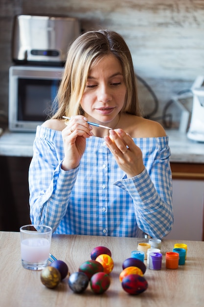 Vacanze, concetto di creazione e fatto a mano: la giovane donna felice attinge all'uovo di Pasqua.