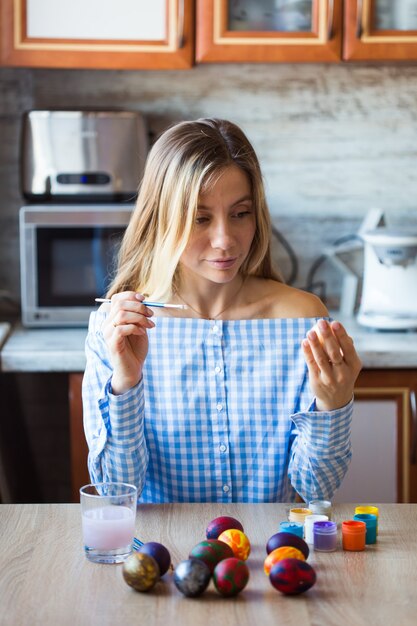 Vacanze, concetto di creazione e fatto a mano: la giovane donna felice attinge all'uovo di Pasqua.