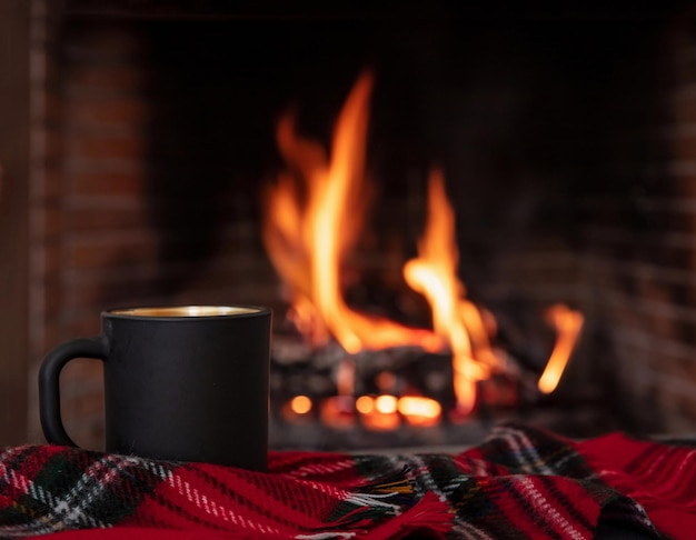 Vacanze di Natale accogliente casa calda Tazza di caffè su un divano coperta camino che brucia lo sfondo