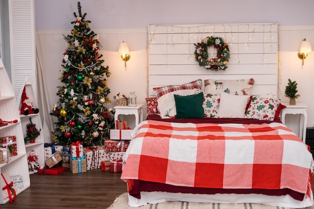 Vacanze di Natale con albero e regali Spaziosa camera da letto a luce bianca in stile loft con un decorato