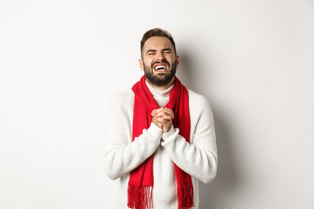 Vacanze di Natale e concetto di Capodanno. Uomo che ha bisogno di chiedere aiuto, supplicare e sembrare infelice, scusarsi per qualcosa, in piedi su sfondo bianco