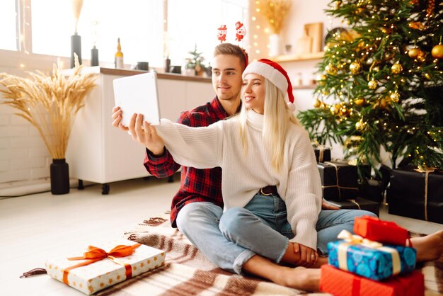 Vacanze di Natale online Giovane coppia che fa una videochiamata con la famiglia o gli amici Incontro virtuale