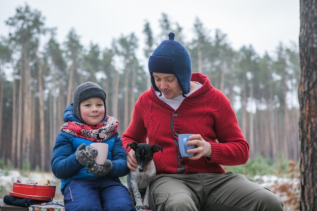 Vacanze di Natale, padre e figlio che bevono bevande calde di Capodanno. Famiglia felice in una passeggiata all'aperto nella soleggiata foresta invernale