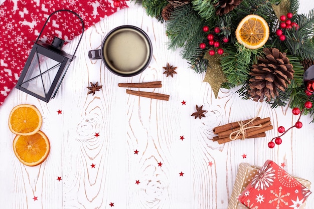 Vacanze di Natale sfondo con abete pigna regali avvolti in carta sciarpa rossa lavorata a maglia con ornamento di cervo tazza di caffè arance essiccate su bianco tavola di legno rustico piatto spazio copia