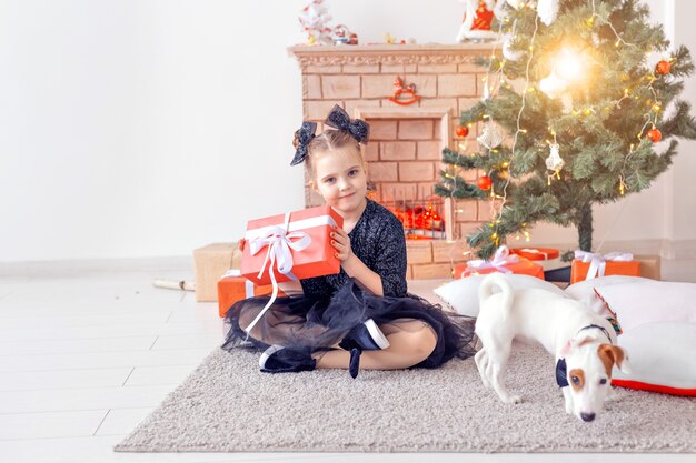 Vacanze e concetto di infanzia - Ritratto di una bambina felice e carina con un regalo di Natale