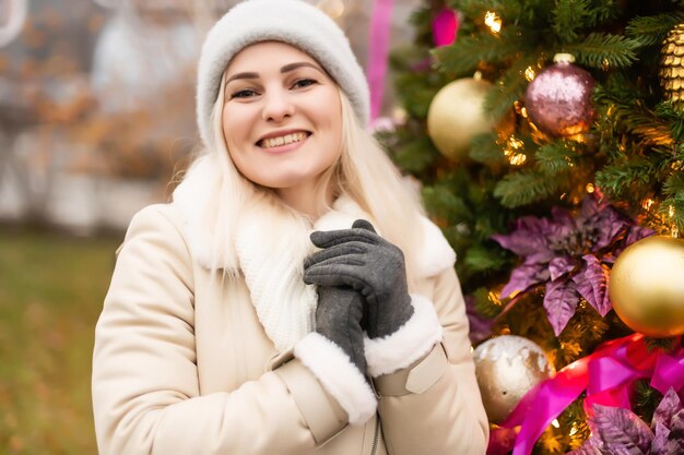 vacanze e concetto di persone - giovane donna in abiti invernali sopra l'albero di natale