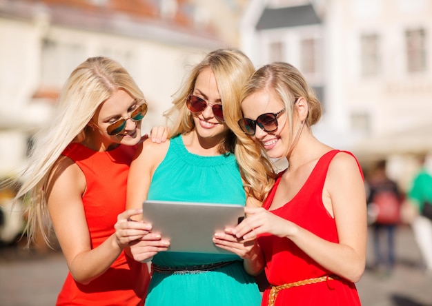 vacanze e concetto di turismo - belle ragazze bionde che guardano il tablet pc in città