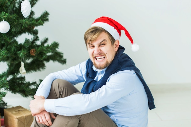 Vacanze, emozione e concetto negativo - uomo arrabbiato sotto l'albero di Natale