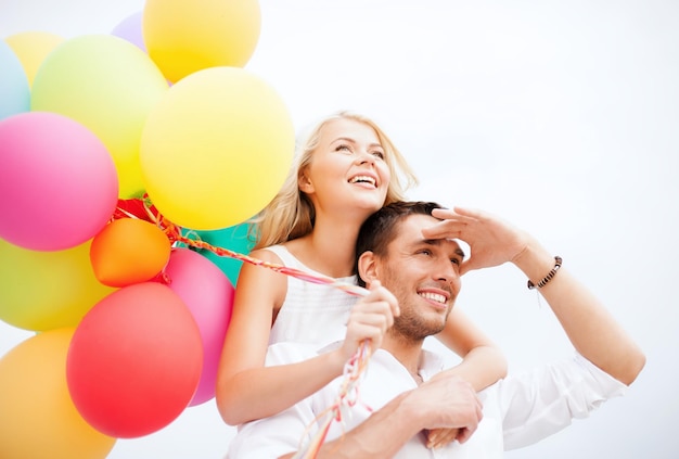 vacanze estive, celebrazione e concetto di appuntamenti - coppia con palloncini colorati in riva al mare