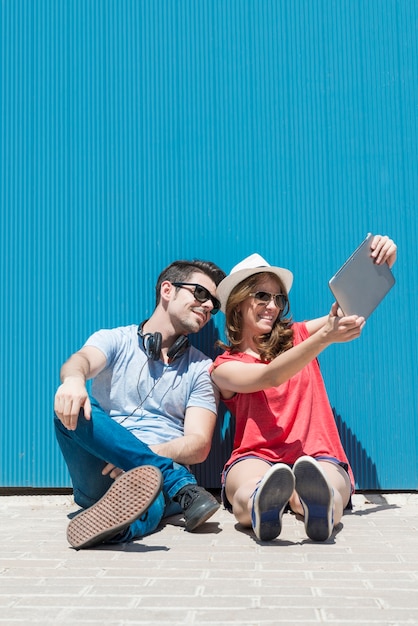 vacanze estive, concetto di adolescente e tecnologia - coppia di adolescenti sorridenti in occhiali da sole che si fanno selfie con un tablet pc