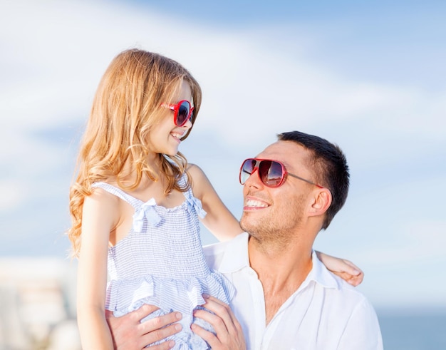 vacanze estive, concetto di bambini e persone - padre e figlio felici in occhiali da sole sopra il cielo blu