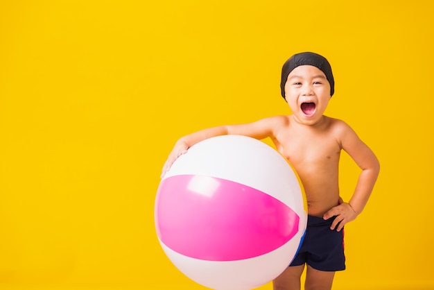 Vacanze estive concetto ritratto felice carino bambino ragazzo sorridente in costume da bagno tenere beach ball