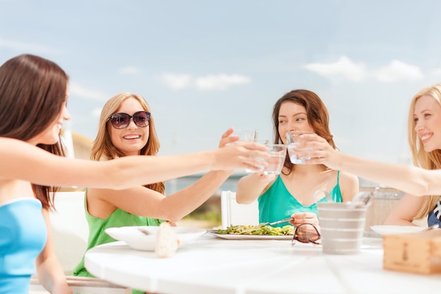 vacanze estive e concetto di vacanza - ragazze che fanno un brindisi in un bar sulla spiaggia