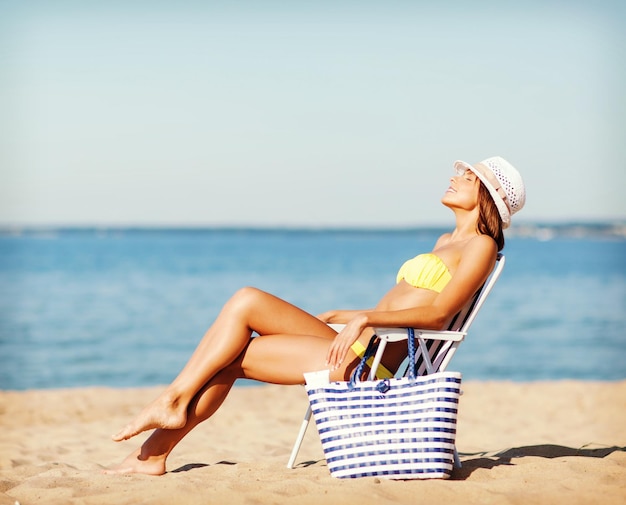 vacanze estive e vacanze - ragazza in bikini che prende il sole sulla sedia a sdraio