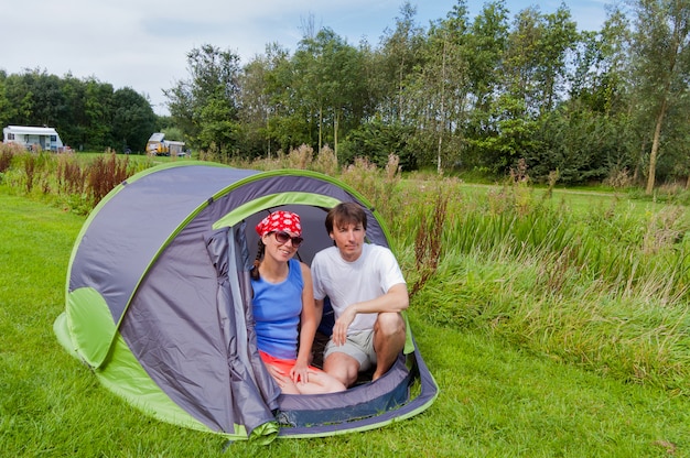 Vacanze estive in famiglia in campeggio. Coppie attive sorridenti felici in tenda.