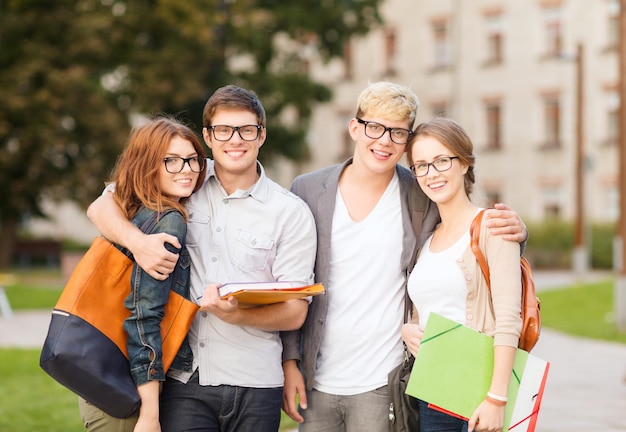 vacanze estive, istruzione, campus e concetto di adolescenti - gruppo di studenti o adolescenti con file, cartelle e occhiali appesi