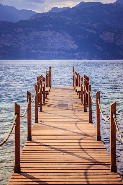 Vacanze estive Molo del bacino di legno sopra l'acqua blu del lago Scenario serale nuvoloso