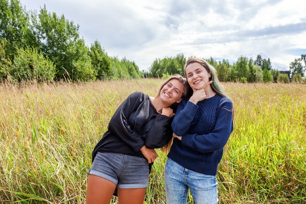 Vacanze estive vacanze concetto di persone felici. Un gruppo di due sorelle amiche che ballano abbracciandosi e si divertono insieme nella natura all'aperto. Momenti incantevoli migliore amica