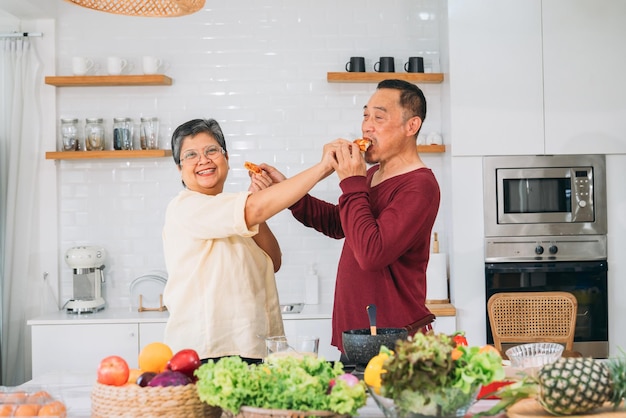 Vacanze felici coppia di anziani che cucinano insieme in cucina abbracciando la gioia culinaria cucinare