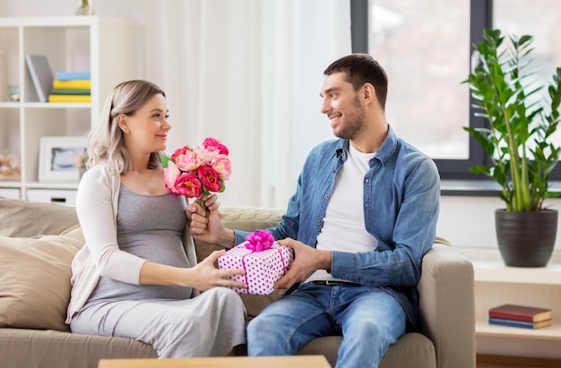 vacanze gravidanza e saluti concetto uomo felice dare fiori a donna incinta a casa