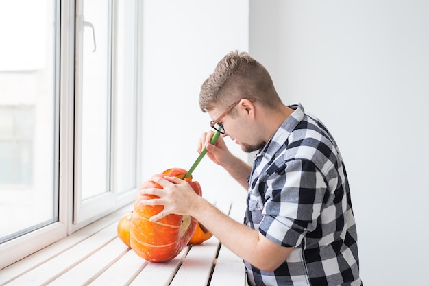 Vacanze, halloween, decorazione e concetto di persone - primo piano dell'uomo con le zucche che si preparano a halloween.