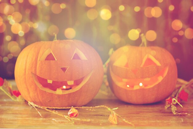 vacanze, halloween e concetto di decorazione - primo piano di zucche intagliate con faccine sorridenti sul tavolo sopra le luci