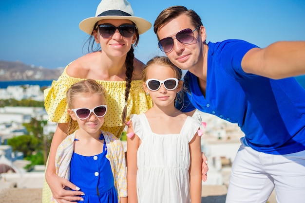 Vacanze in famiglia in Europa. Genitori e figli che prendono selfie nella città di Mykonos in Grecia