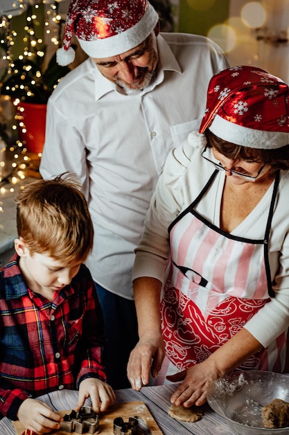 vacanze insieme famiglia nonni con nipote che preparano biscotti di pan di zenzero foto verticale